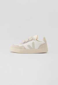 Hvite og beige sneakers med overdel i semsket skinn og syntetisk materiale, med en fremtredende "V"-logo, sikret med borrelåsremmer og en teksturert såle.