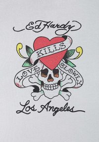 Graphic tričko s červeným srdcem, lebkou a zkříženými kostmi, s nápisy „Ed Hardy“, „Láska zabíjí pomalu“ a „Los Angeles“ v odvážném, barevném designu.