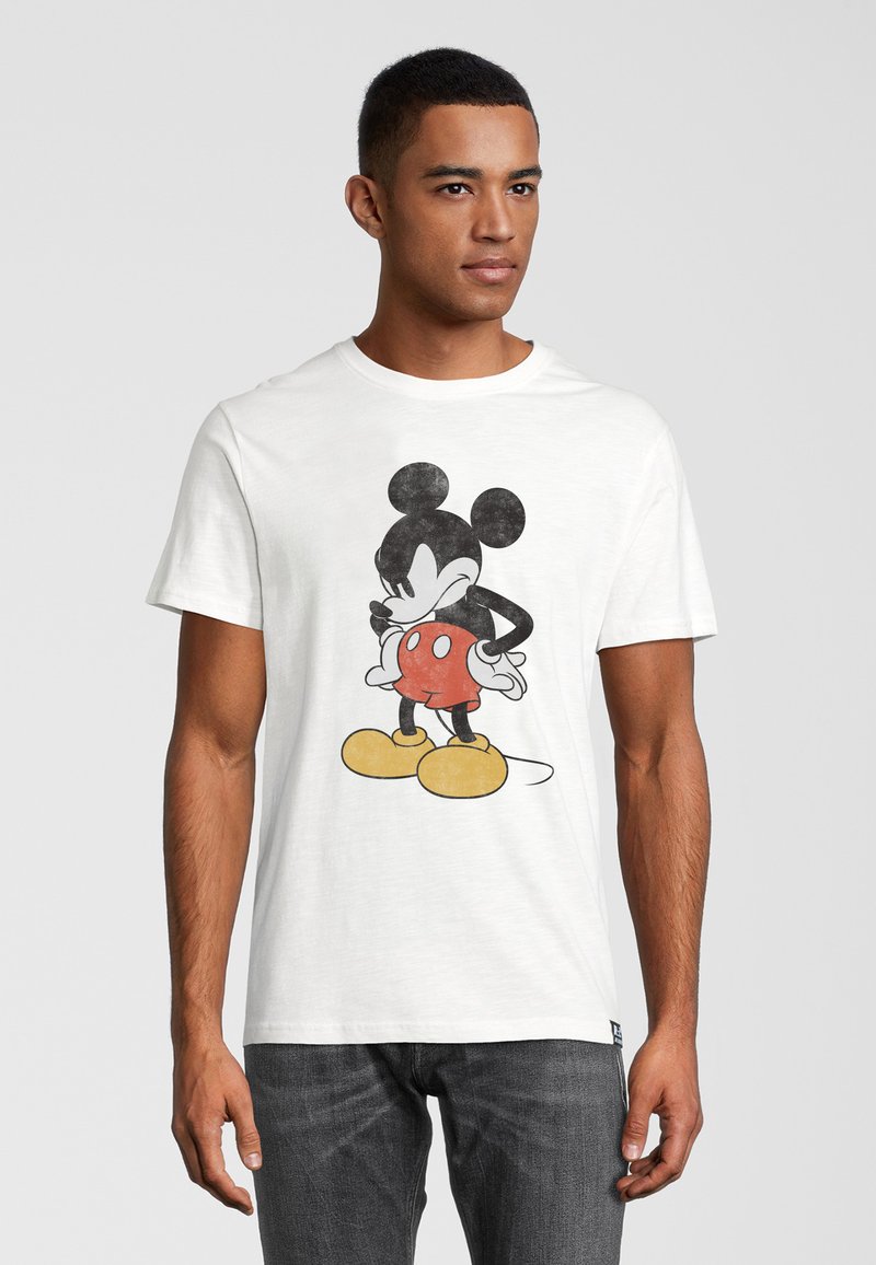 Camiseta de algodón blanca con un gráfico de Mickey Mouse en pantalones cortos rojos y zapatos amarillos, con detalles en negro. Diseño de cuello redondo.