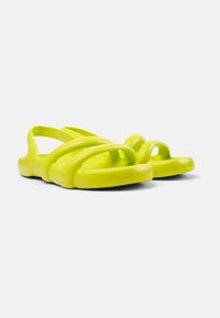 Sandali casual di un vivace giallo neon, realizzati in materiale flessibile con una superficie liscia. Il design presenta diverse cinghie curve e una punta aperta.