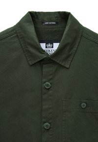 Olivgrüne Button-Down-Hemd mit klassischem Kragen, ausgestattet mit einer Brusttasche auf der linken Seite und passenden grünen Knöpfen. Das Etikett trägt die Aufschrift "ADMIT NOTHING."