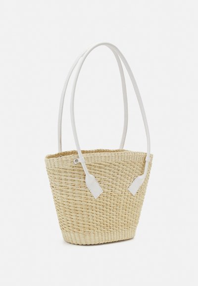 Woven straw tote bag with a beige color, featuring white leather shoulder straps and a tapered shape. Accented with white details at the base.