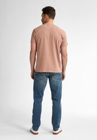 Kurzärmliges, staubig rosa gestreiftes T-Shirt aus Baumwollmix, kombiniert mit blauen Jeans. Sichtbare Nähte und normale Passform.