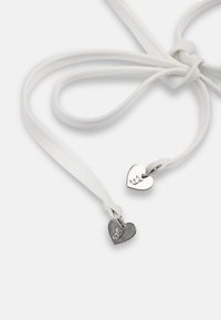 Λευκά δερμάτινα κορδόνια με ασημένια γοητευτικά στοιχεία σε σχήμα καρδιάς, χαραγμένα με "3.1" σε απλό λευκό φόντο.