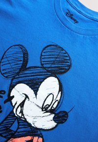 Blue cotton t-shirt featuring a black and white sketch of a cartoon character with large ears. Crew neck design with short sleeves.