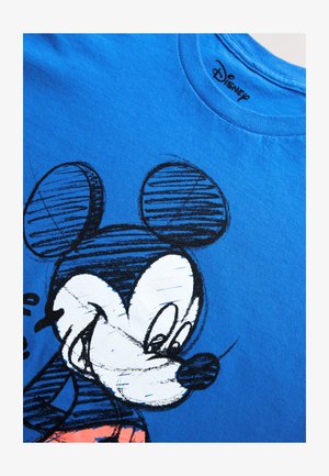 Kék pamut póló, amelyen egy fekete-fehér rajz található egy nagy fülekkel rendelkező rajzfilmfiguráról. Kerek nyakkivágású, rövid ujjú design.