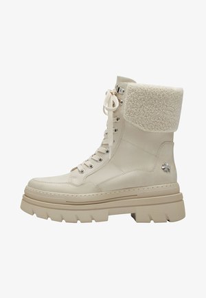 Beige ankle boots with a plush shearling cuff, smooth leather upper, round toe, metal eyelets, and a thick, textured rubber sole.