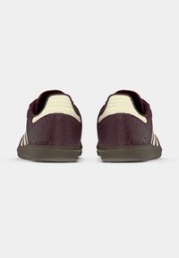 Vínové tenisky s texturovaným vzorem, krémovými akcenty a pryžovou podrážkou. Mají nízký střih a polstrovaný límec pro pohodlí.