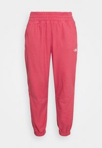Calças de treino cor-de-rosa com cintura elástica e bainhas ajustadas. Apresenta bolsos laterais e um pequeno logotipo branco na perna esquerda. Tecido suave.