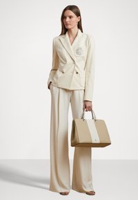 Beige tailored blazer with double-breasted design and patch pocket. Paired with wide-leg beige pants and a structured beige handbag.