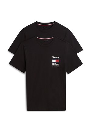 Deux t-shirts noirs à manches courtes Tommy Hilfiger, l'un superposé devant l'autre, avec logo et motif de drapeau sur le côté gauche de la poitrine avant.