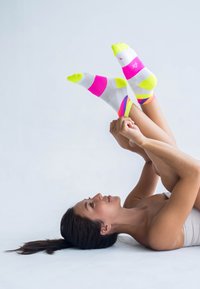 Helle, bunt gestreifte Sportsocken in Pink, Gelb und Weiß mit einem Netzstoff für Atmungsaktivität, die ein sportliches Design präsentieren.