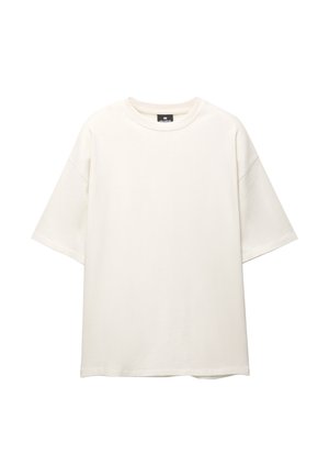 Túlméretes, krémszínű pamut póló. Rövid ujjú, kerek nyakkivágással rendelkezik, és laza fazonú, látható minták vagy díszítések nélkül.