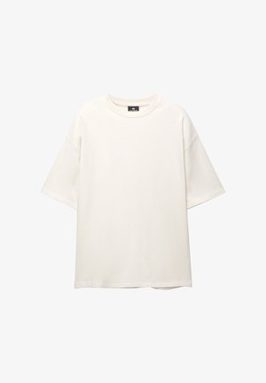 Tricou supradimensionat, de culoare crem, din bumbac. Are mâneci scurte, o guler rotund și o croială confortabilă, fără modele sau accente vizibile.