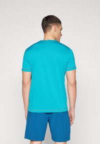 Turquoise short-sleeve athletic shirt with gray trim, features a round neckline and lightweight material, paired with dark blue shorts.