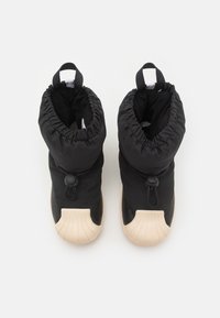 Černé nadýchané kotníkové boty s našitou horní částí, zapínáním na západku a krémovou gumovou podrážkou s texturovanou špičkou.