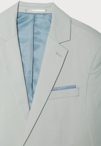 Sacou gri deschis cu rever șal, căptușeală albastră și batistă în albastru deschis. Textură netedă cu detalii personalizate.
