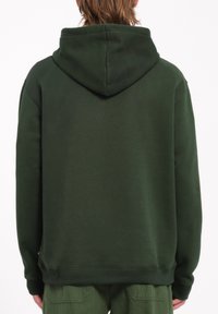 Sudadera verde con una textura suave, que presenta una gran capucha y puños acanalados. La parte posterior muestra un diseño simple y limpio sin acentos adicionales.