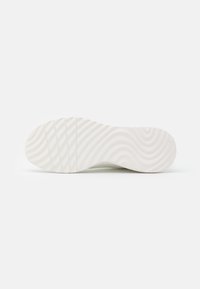 White rubber shoe sole with wave pattern, featuring six raised sections near the heel and smooth surface near the toe.