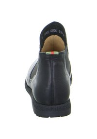 Scarpa in pelle nera con punta arrotondata, retro texturizzato e suola imbottita. Presenta un piccolo accento colorato vicino al tallone.