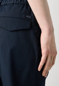 Mörkblå skräddarsydda byxor med en subtil ribbad textur, med en bakficka med en BOSS-logotag och ett elastiskt midjeband.