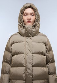 Giubbotto imbottito beige con colletto alto e cappuccio regolabile con cordino. Design a righe orizzontali. Materiale esterno liscio e lucido.