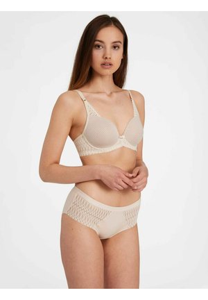 Reggiseno in pizzo beige con una superficie liscia e ferretto, caratterizzato da un bordo in pizzo decorativo. Slip beige coordinato con dettagli in pizzo sui lati.