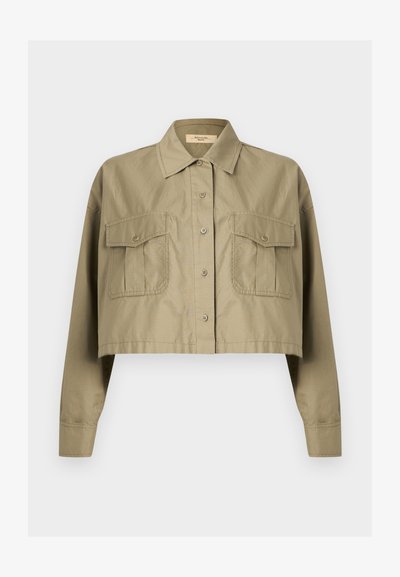 Περικομμένο χακί πουκάμισο με μακριά μανίκια, κουμπιά, μυτερό γιακά και δύο τσεπάκια στο στήθος με κουμπιά.