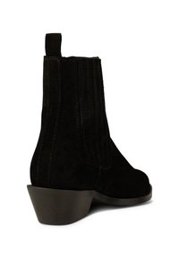 Botines de ante negro con paneles laterales elásticos, punta redondeada y tacón bajo cuadrado. Incluyen una tira en la parte posterior para facilitar su uso.