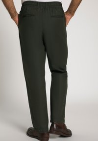 Pantaloni verde scuro con vita elastica, due tasche posteriori e design a gamba dritta, abbinati a scarpe marroni.