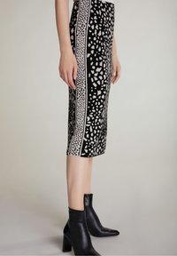 Polvipituinen kynähame mustana, jossa on abstrakti valkoinen kuvio ja kontrastiväriset harmaat sivupaneelit. Yhdistetty mustiin nilkkasaappaisiin.