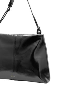 Svart läderhandväska med glänsande yta, som har en strukturerad form och en enkel axelrem. Minimalistisk design med en logotypdetalj.