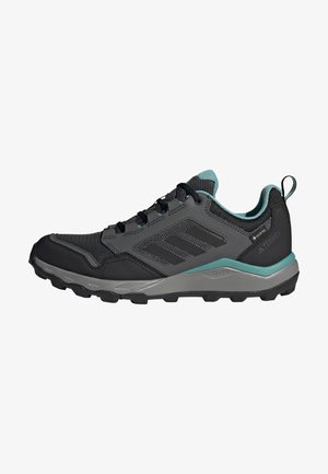 Zapatillas de trail running en negro y verde azulado, con una parte superior de malla, suela de goma duradera y acentos texturizados para mejorar el agarre.