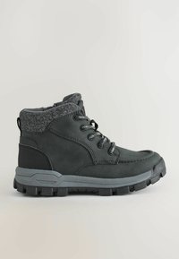 Bottes imperméables gris foncé avec un col en feutre gris, semelle en caoutchouc texturée, laçage à six œillets et détails sur le côté. Convient aux terrains accidentés.