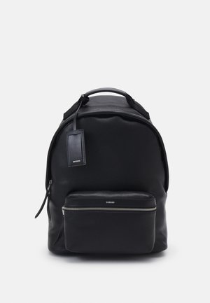 Mochila negra de cuero con acabado texturizado, forma redondeada, asa superior, bolsillo con cremallera en la parte frontal y etiqueta de la marca.