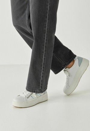 Vita sneakers med ljusblå accenter, snörning och en tjock sula, kombinerade med mörkgrå jeans med rak ben.