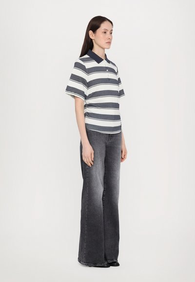 Polo skjorte med marineblå og hvite horisontale striper, korte ermer; kombinert med høyhælte, flagrende grå jeans. Enkle svarte sko.
