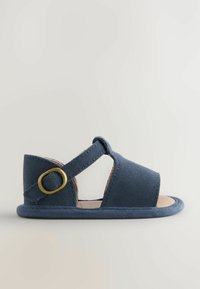 Sandalo in suede blu navy con design a cinturino incrociato, lati aperti e punta tonda. Caratterizzato da un dettaglio con fibbia dorata e una soletta beige.
