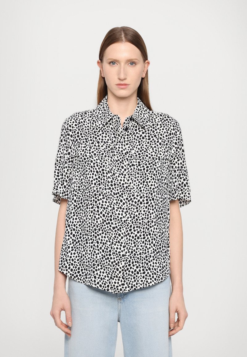 Short-sleeve button-up shirt in lightweight fabric, featuring a black and white spotted pattern, and a straight hem with front pockets.