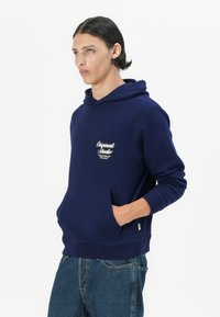 Navyblauwe hoodie van een katoenen mix, met een zak aan de voorkant, ribgebreide boorden en een klein wit logo op de borst. Klassiek pullover ontwerp.