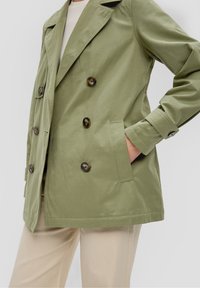 Olive green double-breasted jacket made of smooth fabric, featuring large brown buttons, side pockets, and a structured collar.