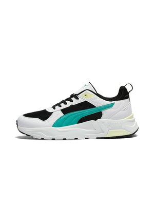 Zapatilla deportiva blanca y negra con una franja lateral en verde azulado, cordones negros, suela blanca gruesa y una lengüeta en el talón.