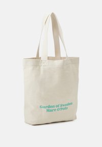 Borsa a spalla in canvas, colore beige cremoso, con testo azzurro chiaro "Garden of Sweden Marc O'Polo". Due manici resistenti e coordinati. Forma semplice e rettangolare.