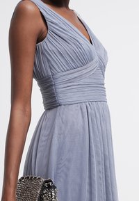 Light blue dress with pleated texture, v-neck, and gathered waistband. Includes a small chain-patterned handbag.