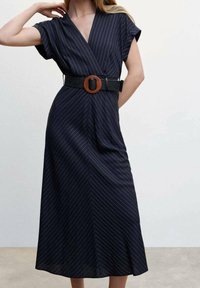 Navy wrap-mekko, jossa on valkoisia pystyraitoja, lyhyet hihat ja kiristetty vyötärö leveällä mustalla vyöllä, jossa on pyöreä puinen solki.