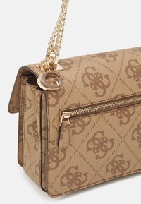 Sac à main beige et marron à motifs avec bandoulière chaîne dorée, poche avant zippée et breloque dorée en forme de "G" attachée à l’anneau de la bandoulière.