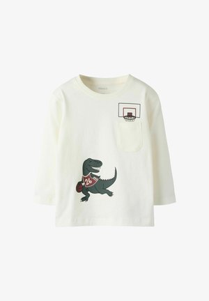 Chemise blanche à manches longues avec un graphisme de dinosaure vert tenant un ballon de basket, maillot rouge avec le chiffre "26", et détail de poche en forme de panier de basket.