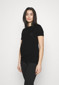Tricou negru, fit ajustat, cu mâneci scurte și decolteu circular, realizat dintr-un material neted. Modelul îl asortează cu colanți negri.