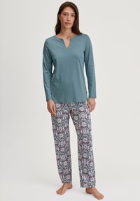 Langarm teal bovenstuk met een V-hals, gecombineerd met gestreepte pyjamabroek met bloemendessins in roze en grijs op een lichte achtergrond.