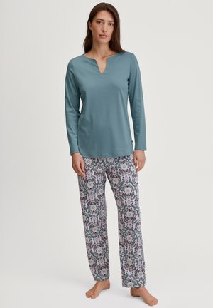 Top teal a maniche lunghe con scollo a V, abbinato a pantaloni da pigiama con fantasia floreale in rosa e grigio su uno sfondo chiaro.